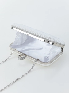 Detail of white bridal clutch bag with pearls, rhinestones and silver metal chain
