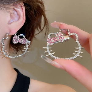 Macro detail of rhinestone hollow cat earrings with pink crystal bow accents