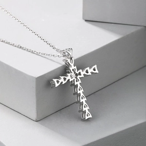 Detailed close-up of a silver heart-shaped cross pendant on a minimalist stone display