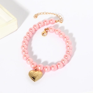 Macro detail of a pink pearl pet necklace featuring a gold heart-shaped Love pendant