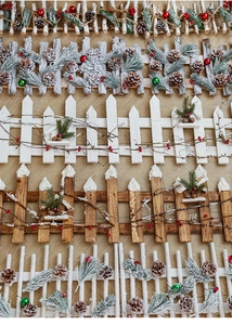 Detailed view of various miniature wooden Christmas fences with pine cones and red berries