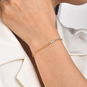 Detail of a gold link bracelet featuring sparkling white zircon stones on a female wrist