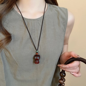 Detail of wooden cat pendant necklace with blue crystal eyes and colorful accent beads