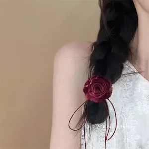 Detail of wine red fabric rose hair tie on braided hair with long satin ribbons