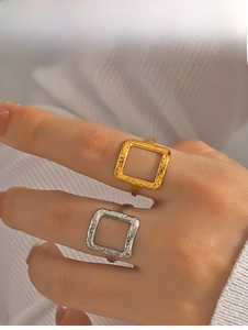 Close-up of gold and silver square rings with hammered texture on model hands