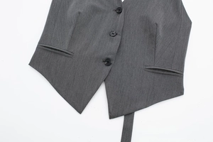 Détail du gilet gris foncé avec trois boutons, poches passepoilées et texture fine