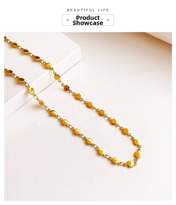 Detailed close-up of golden double heart chain necklace on a minimalist white display