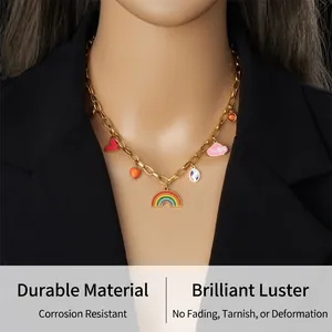 Détail d'un collier chaîne doré avec breloques émaillées arc-en-ciel et cœur sur un mannequin