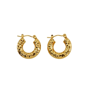 Detailed macro view of gold U-shaped earrings with textured hammered finish texture