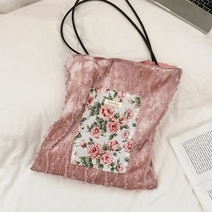 Close-up of pink velvet tote bag with floral patch, brand label and ruffled details
