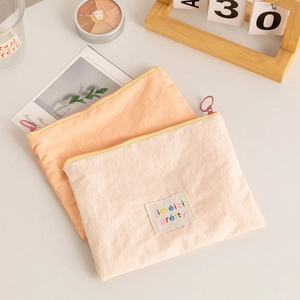 Close-up of cream and orange nylon makeup pouches with rainbow letter patches and ring zippers