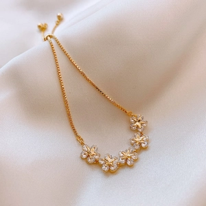Detail of gold flower bracelet with sparkling zircons on elegant silk background