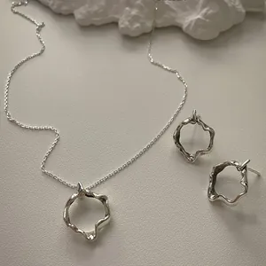 Close-up of 925 silver liquid lava irregular jewelry set on a minimalist background