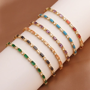 Golden tennis bracelets set with colorful cubic zirconia displayed on a white holder