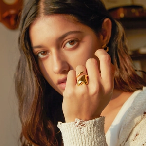 Close-up of 18k gold heart-shaped open ring on finger with warm caramel lighting