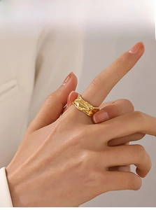 Detailed view of an irregular wrinkled gold-plated adjustable ring worn on a finger