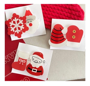 Detail view of cute resin Santa Claus and Christmas tree hair clips on red knit fabric