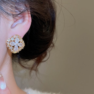 Macro close-up of a gold-plated floral stud earring with sparkling zircon petals