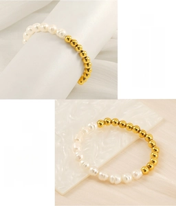 Détail du bracelet en perles d'eau douce et acier inoxydable doré sur de la soie