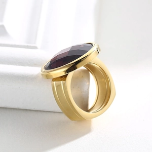 Detailed close-up of a gold-plated ring featuring a large faceted deep purple gemstone