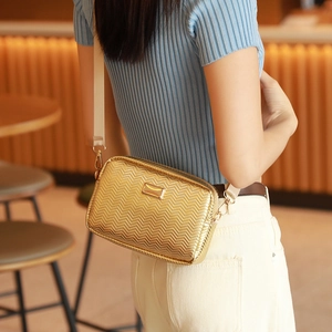 Sac caméra doré chic avec motif à chevrons et bandoulière beige sur un mannequin