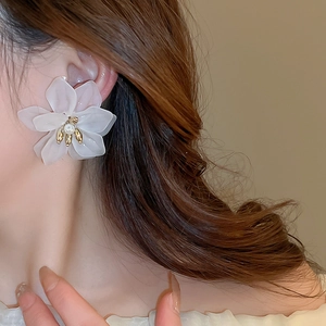 Close-up of white matte flower earrings with gold metal stamen worn by model