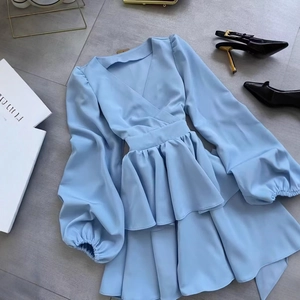 Detail of light blue V-neck dress featuring layered ruffle hem and elasticated cuffs