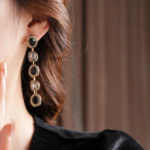Détail de boucles d'oreilles vintage dorées avec pierres noires sur un mannequin