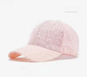 Close-up of the fuzzy fringe texture and light pink fabric of the summer baseball cap