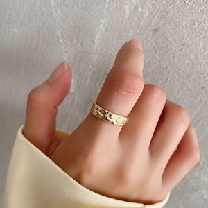 Detail of a hammered texture gold-plated ring on index finger with artistic finish
