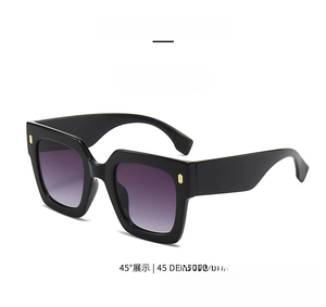 Detail view of square black sunglasses with gradient lenses and golden hinge decor