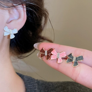 Detail of colorful bow stud earrings featuring sparkling rhinestones and glossy finish
