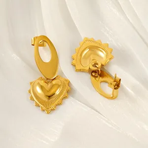 Fashionable gold stainless steel heart earrings with radiant texture on white silk backdrop