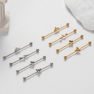 Detailed view of silver and gold industrial barbells with crown and snake charms