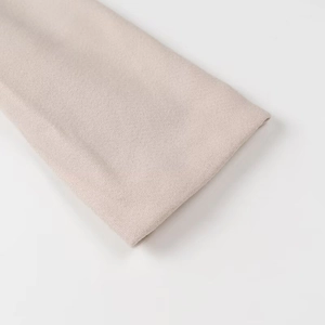 Close-up of beige wool jacket cuff showing premium fabric texture and neat stitching