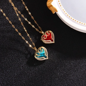 Elegant gold heart necklaces with red and blue crystal pendants on black leather background