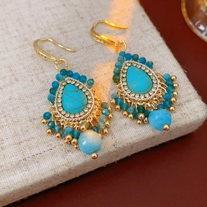 Vue détaillée des boucles d'oreilles bohèmes avec pierres turquoise et perles dorées