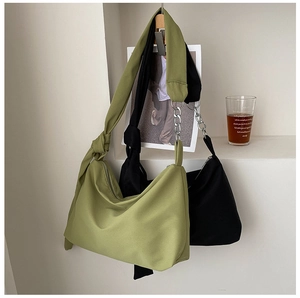 Detail of canvas crossbody bag with metal chain and knot strap in green and black