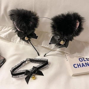 Détail d'oreilles de chat en peluche noire, tour de cou en dentelle et grelots dorés