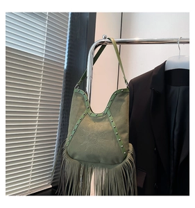 Close-up of green bohemian fringe shoulder bag with suede texture and sun face relief