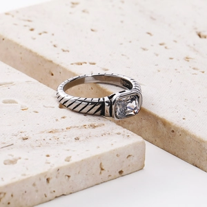 Detailed macro view of silver ring featuring a large square zircon and textured spiral band