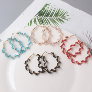 Detail of colorful beaded hoop earrings in gold frames set on a white plate