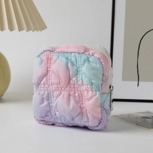Close-up of quilted tie-dye cosmetic bag with silver zipper on a minimalist desk