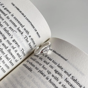 Elegant 925 sterling silver open ring with a heart-shaped zircon placed on an open book