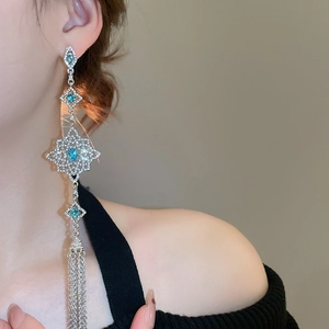 Close-up of long tassel earrings with blue gemstones and silver diamond inlay