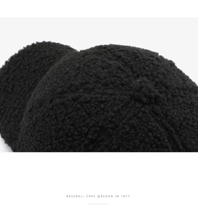 Dettaglio della trama in pile sherpa nero e ricamo sul cappellino da baseball invernale