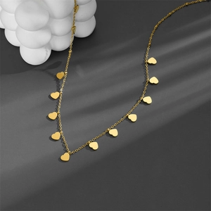 Polished gold heart charm necklace detail on a minimalist grey background with artistic shadows