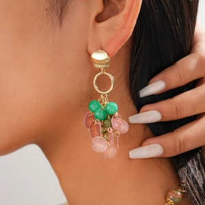 Detailed shot of long bohemian drop earrings with gold metal rings and green stone beads