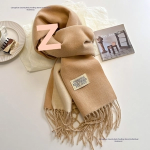 Detail of beige cashmere-feel scarf featuring soft tassels and a woven brand label