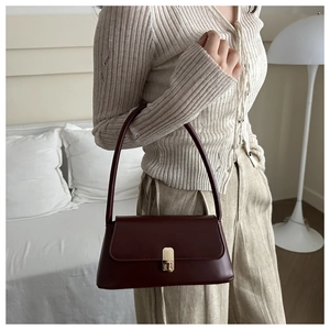 Detail shot of vintage burgundy leather handbag with gold clasp and elegant shoulder strap